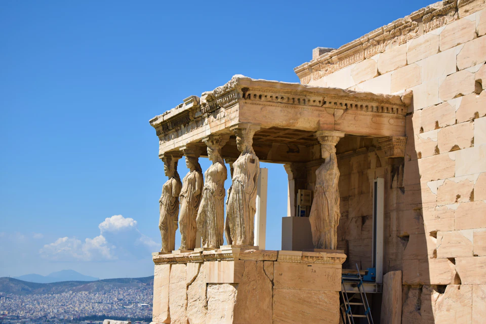 A section of the Erechtheion temple in Athens, featuring the Caryatids, with a clear blue sky in the background.