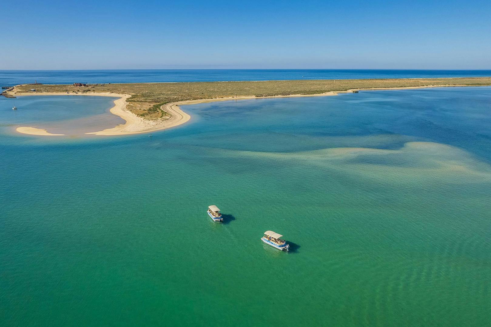Лодки Formosamar возле острова Дезерта с чистыми бирюзовыми водами и живописными видами на побережье под ярким голубым небом.