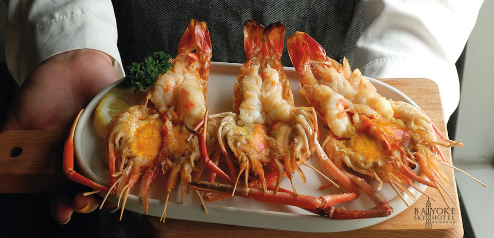 Three grilled lobsters garnished with parsley on a white plate.