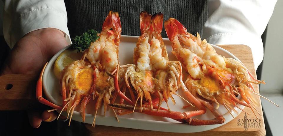 Three grilled lobsters garnished with parsley on a white plate.