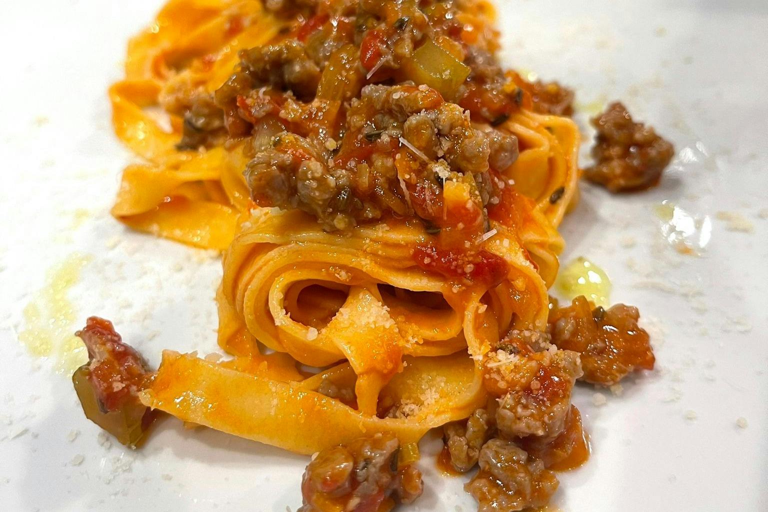 Fresh pasta topped with a chunky meat and tomato sauce, garnished with grated cheese.