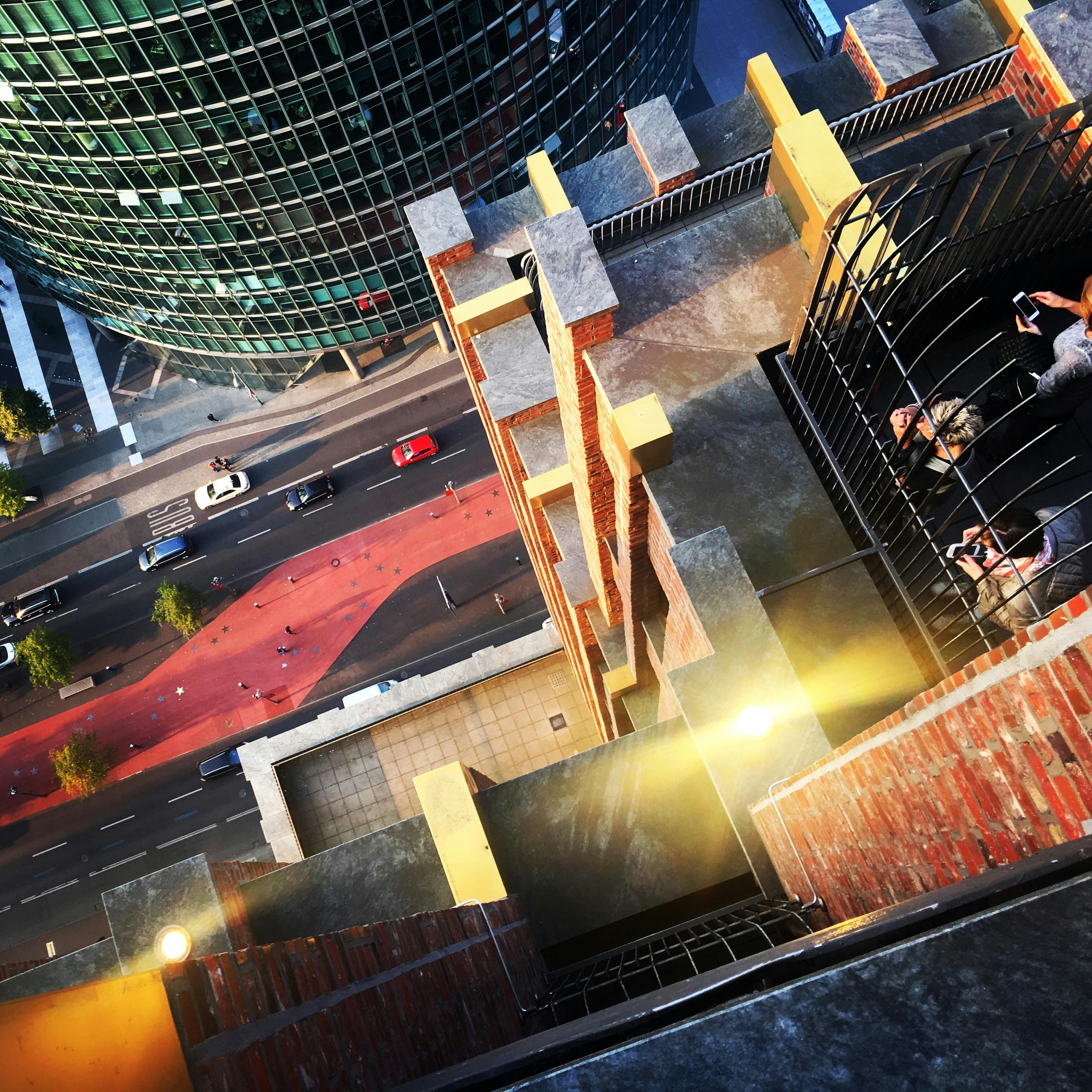 Een hoge hoekopname van een stadsstraat met auto&#39;s en een rood voetgangerspad, grenzend aan een hoog, cilindervormig glazen gebouw.