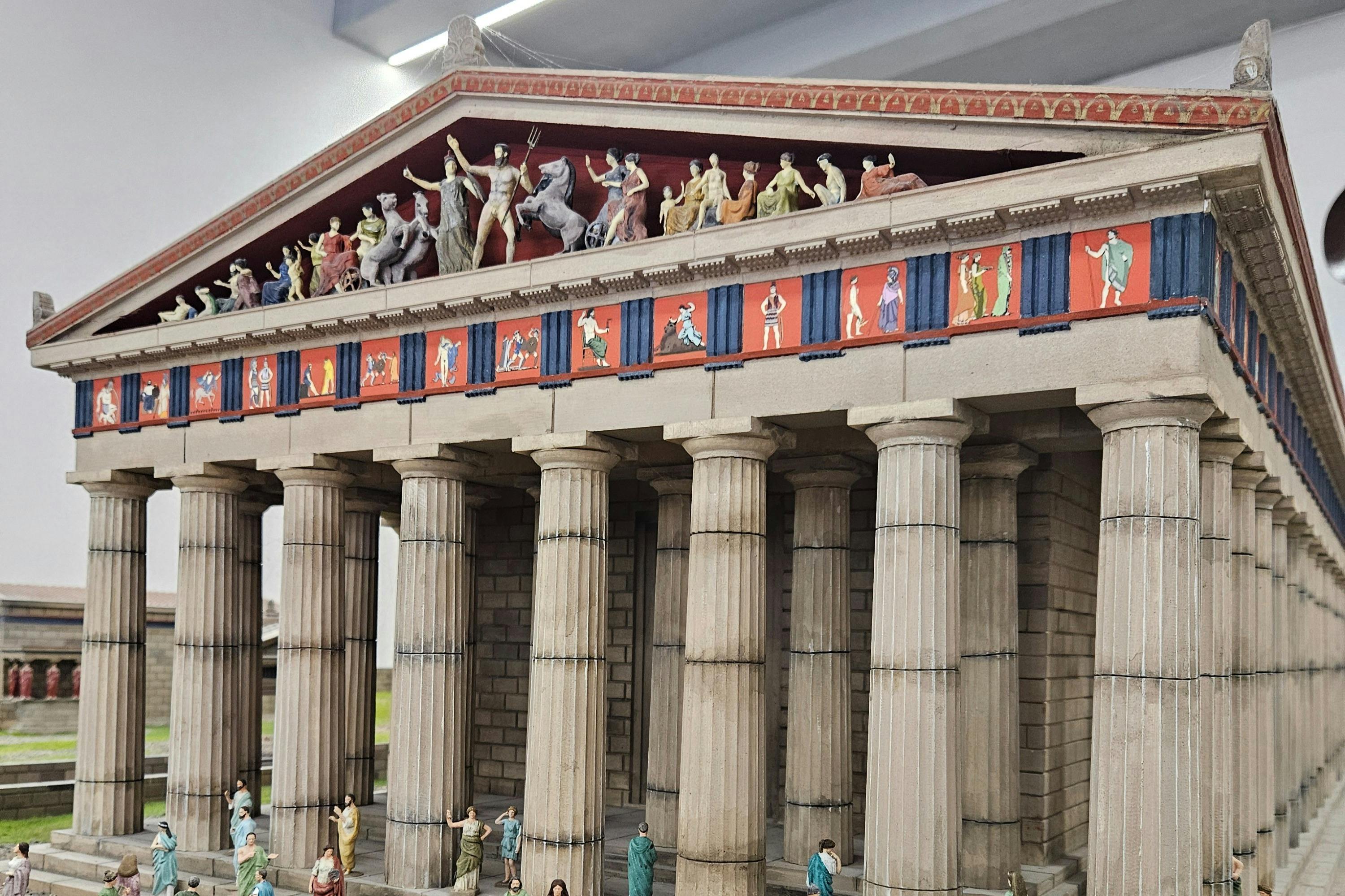 古典希腊神庙的模型，带有油漆的饰边、细节柱和台阶和屋顶上的微型人物。