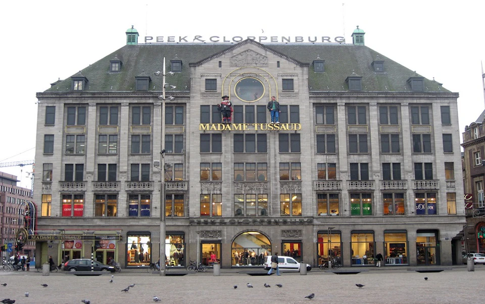 A multi-story building with "Madame Tussaud" and "Peek & Cloppenburg" signs, showcasing shop displays on the ground floor.