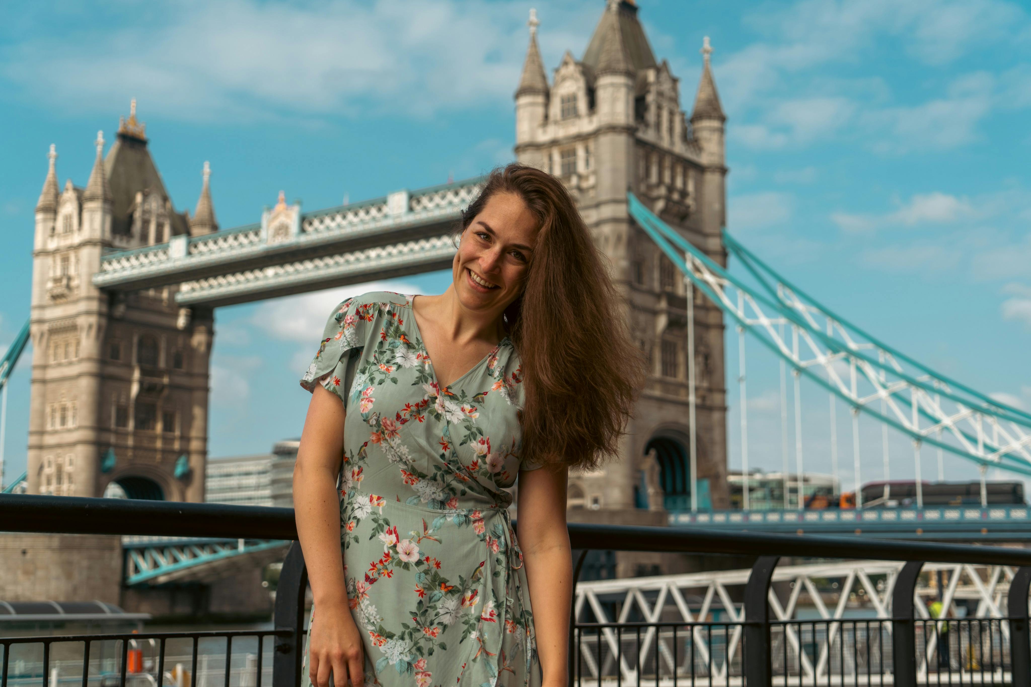 A tourist is having her photo taken outside the Tower Bridge.
