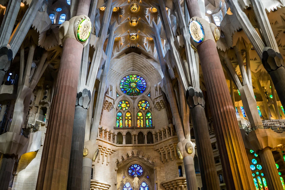 Interior of a cathedral with tall columns, intricate arches, and colorful stained glass windows.