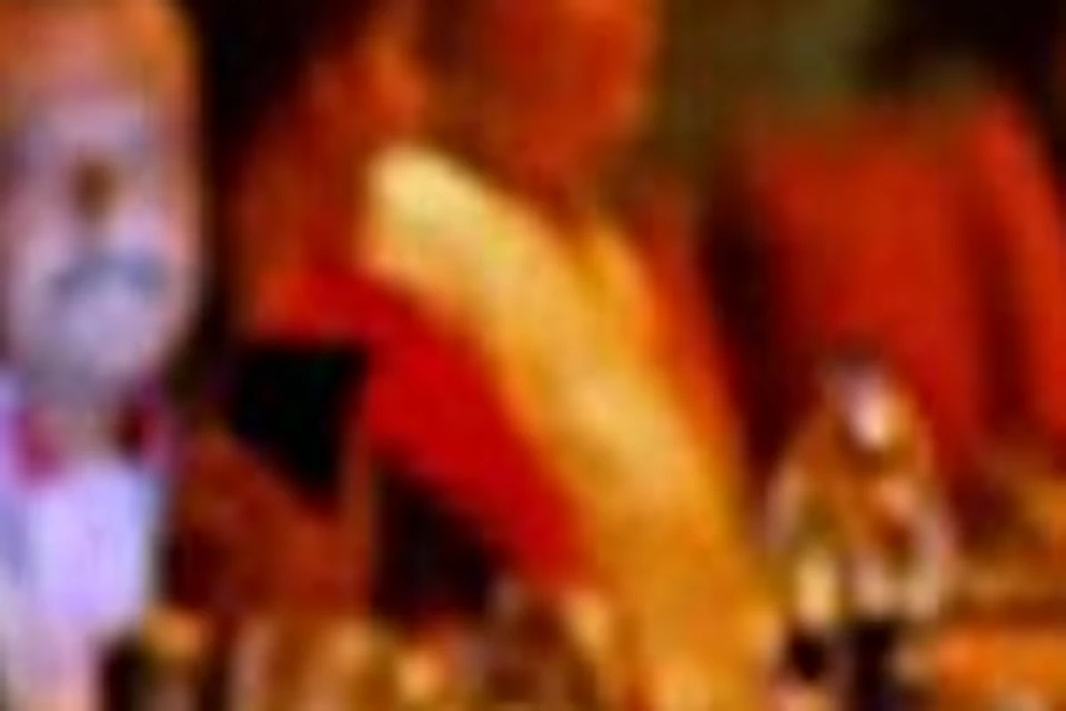 A warmly lit, crowded restaurant with people sitting at tables, engaged in conversation, and waitstaff serving food and drinks.