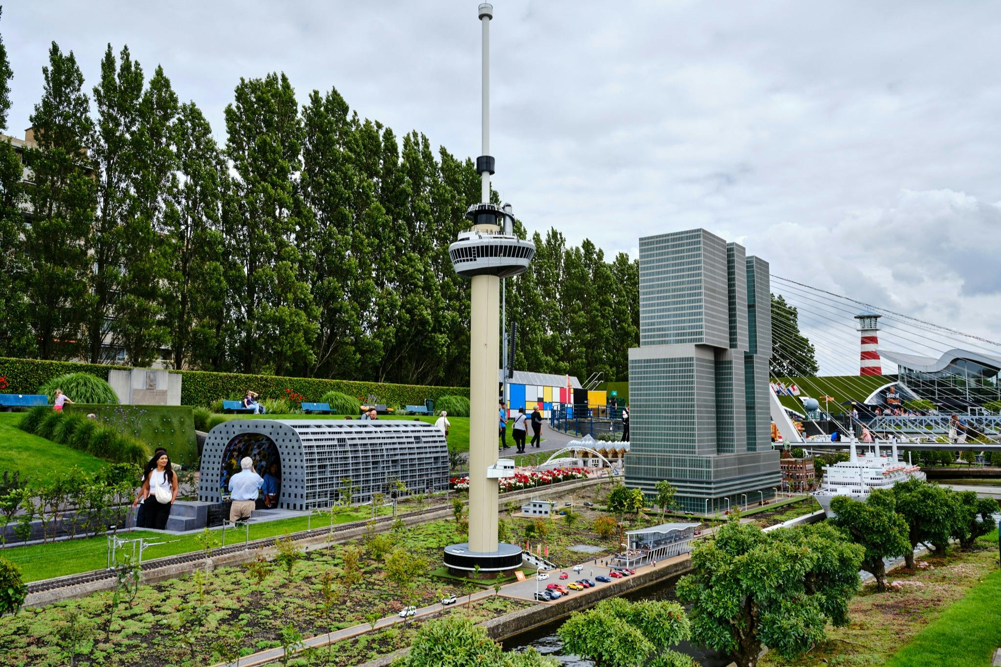 녹지로 둘러싸인 높은 타워, 현대적인 건물, 기차역이 특징인 도시 풍경의 미니어처 모델입니다.