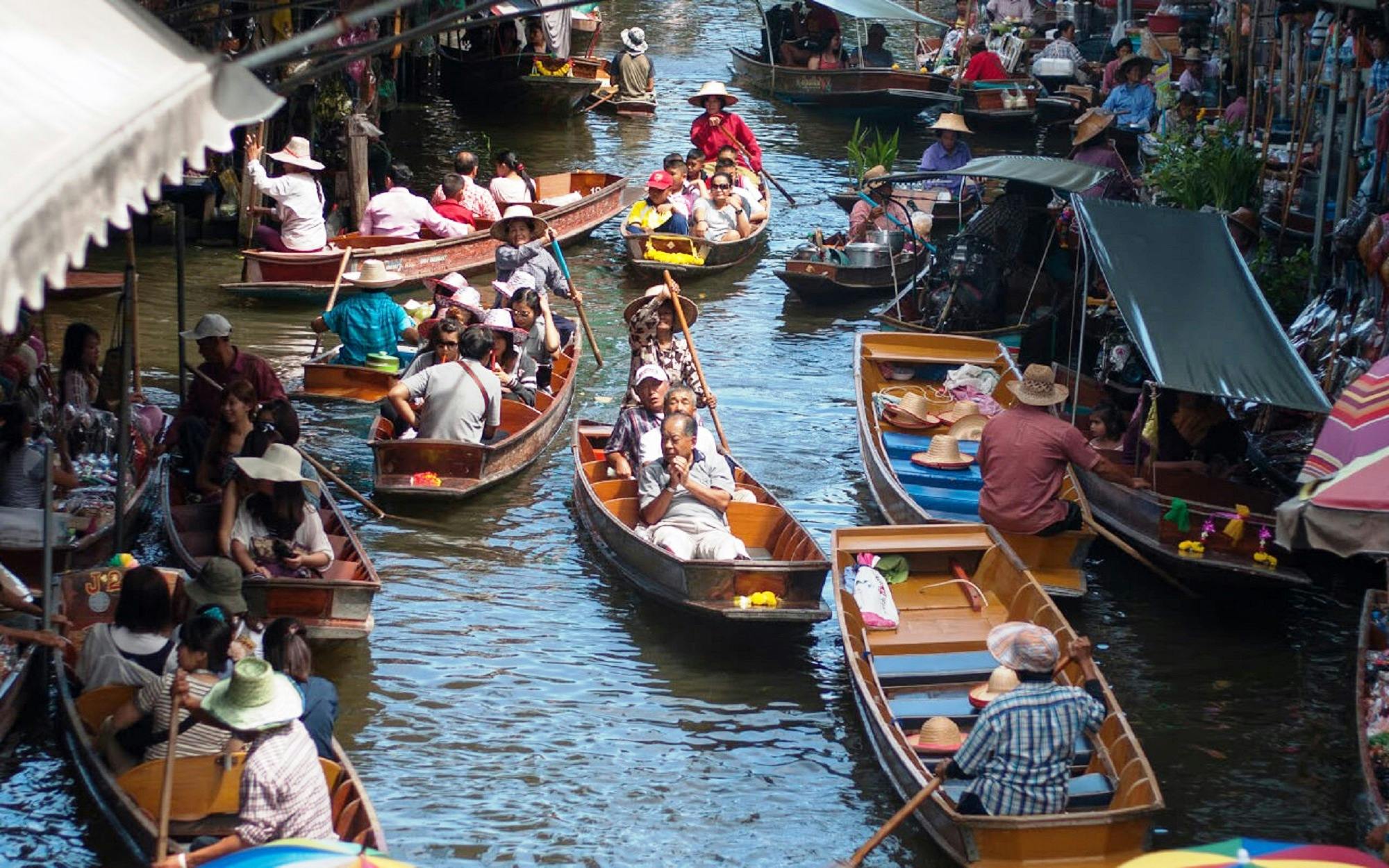 拥挤的水上市场，人们乘坐木船，有些人出售商品，有些人在运河上划桨。