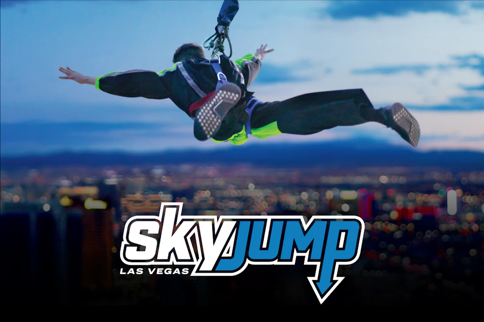 Person in a harness jumping off a platform with blurred cityscape in the background; "skyjump LAS VEGAS" text overlay.