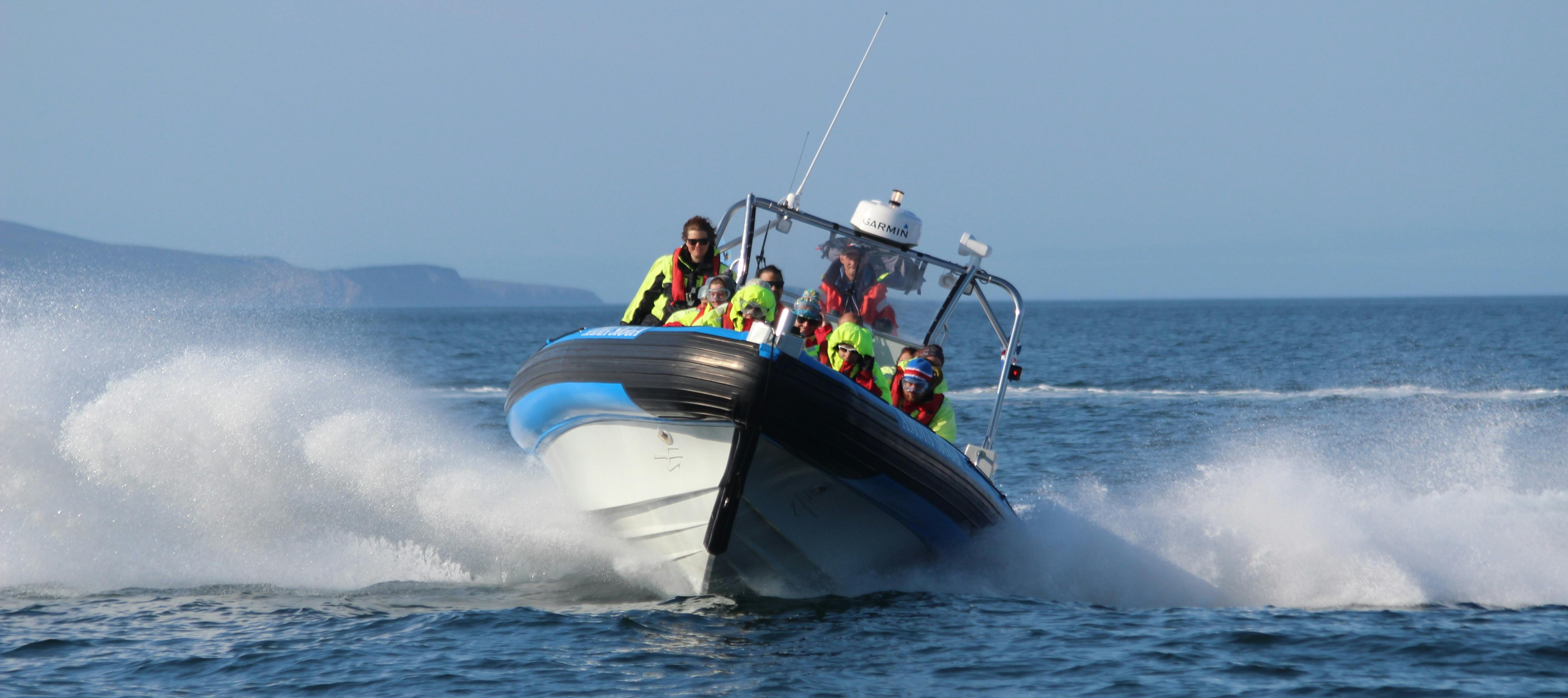 맑은 날 물속에서 과속하는 네온 안전 장비를 착용한 승객이 탑승한 스피드보트.