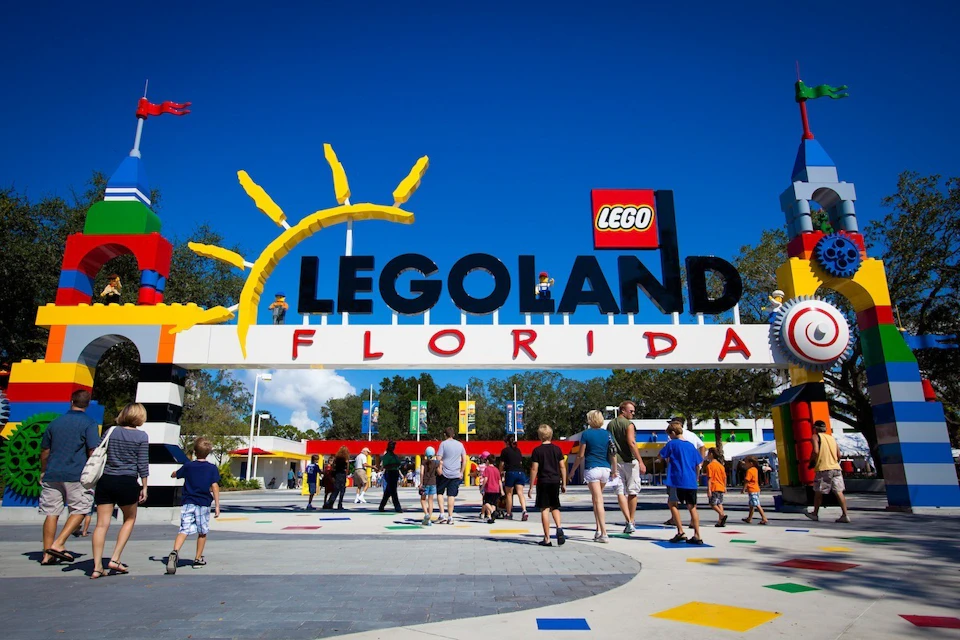 Entrance to LEGOLAND Florida with people walking under a colorful LEGO-themed arch on a sunny day.