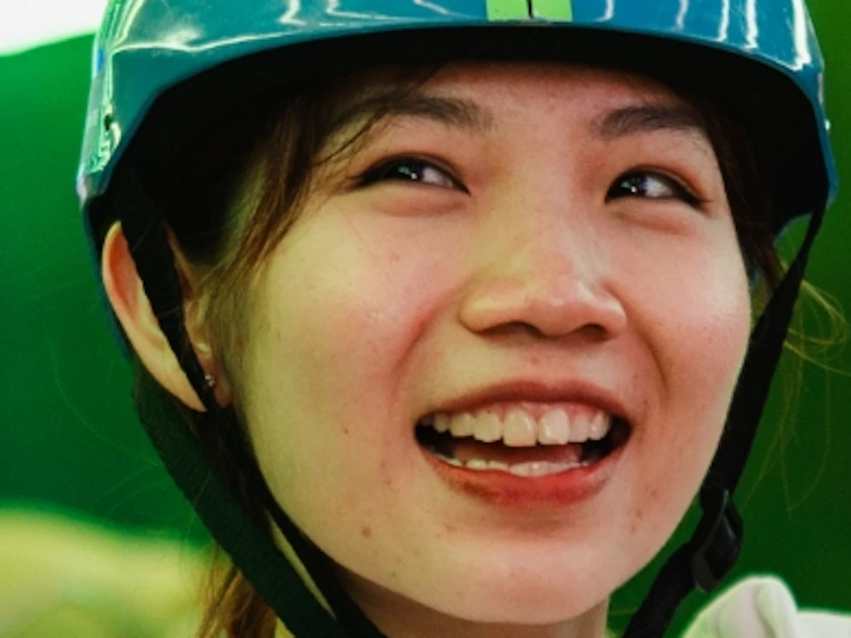 Four people riding go-karts in a tunnel with green lights, smiling and enjoying the activity.