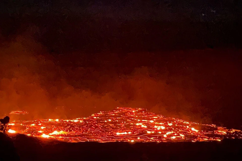 A glowing pile of molten lava with bright orange and red hues, emitting light against a dark, smoky background.