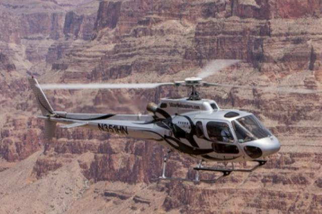 A helicopter flies over a rocky canyon landscape with visible markings and spinning rotor blades.