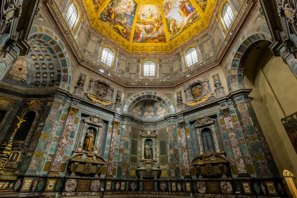 Interior view of an ornate church or chapel with statues, elaborate decorations, and a painted domed ceiling.