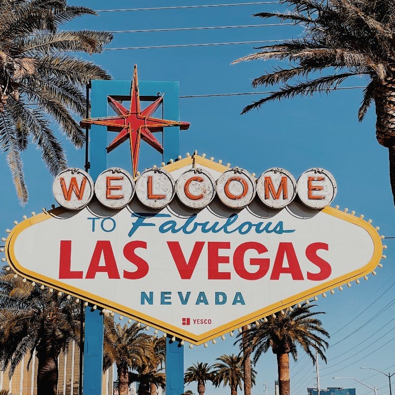 "Welcome to Fabulous Las Vegas, Nevada" sign, surrounded by palm trees under a clear blue sky.