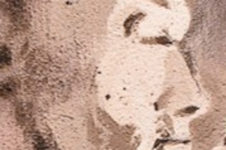 A person photographs a mural of a couple embracing, each holding a phone, painted on a brick wall.