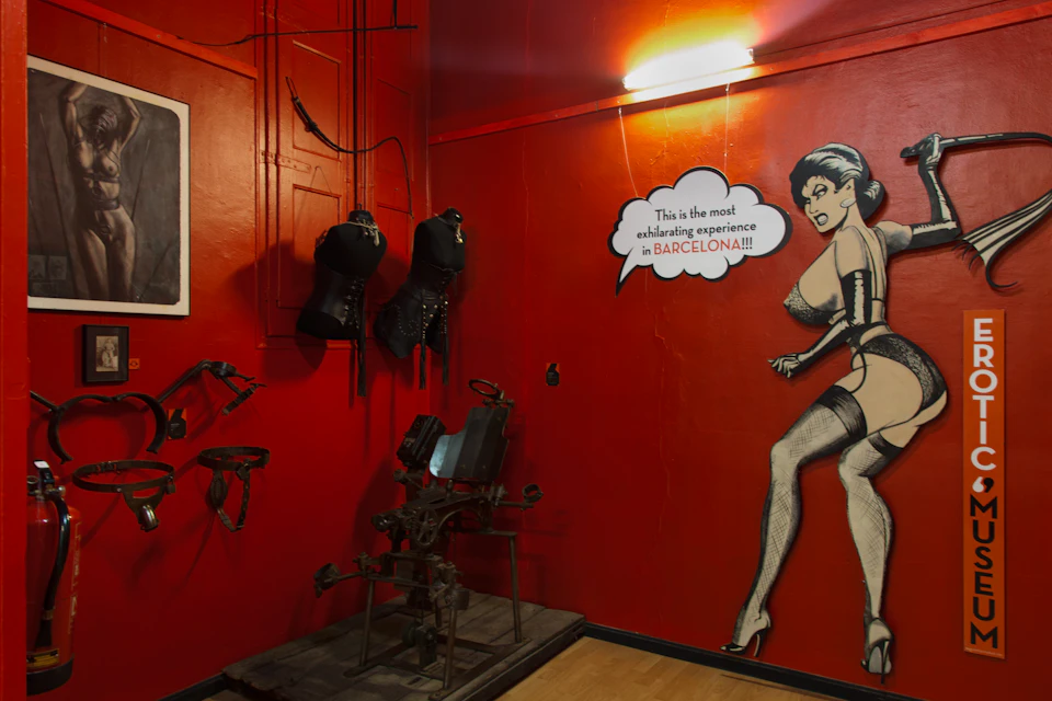 Room with red walls featuring a large caricature of a woman in lingerie, a bubble text, and a sign reading "Erotic Museum."