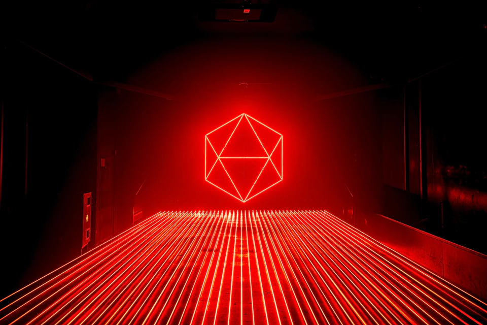 A glowing red geometric shape on a dark background, with horizontal red light beams extending toward the viewer.