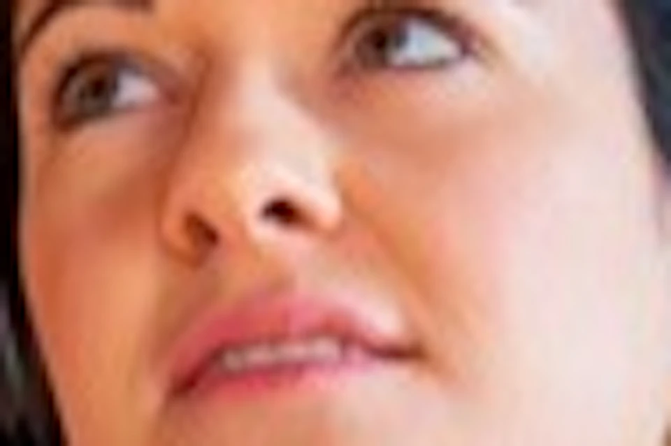A woman with headphones and a device stands in an ornate gallery with red walls and a decorated ceiling.