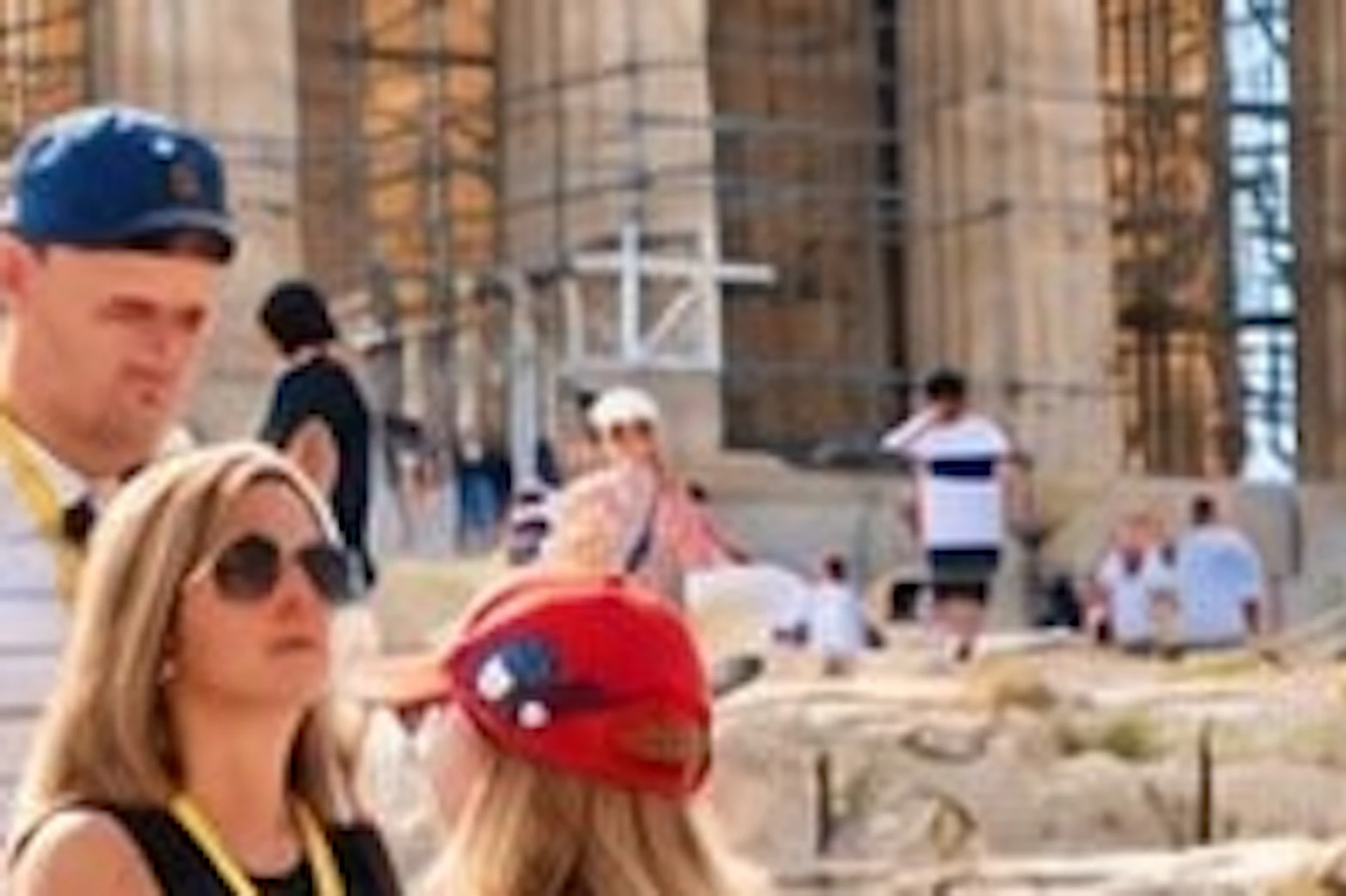 A group of tourists standing in front of the Parthenon on a sunny day, observing the ancient structure.