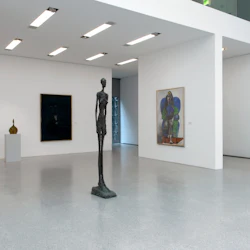 Rymligt, modernt konstgalleri med abstrakta skulpturer och målningar, med vita väggar och polerade, ljusgrå golv.