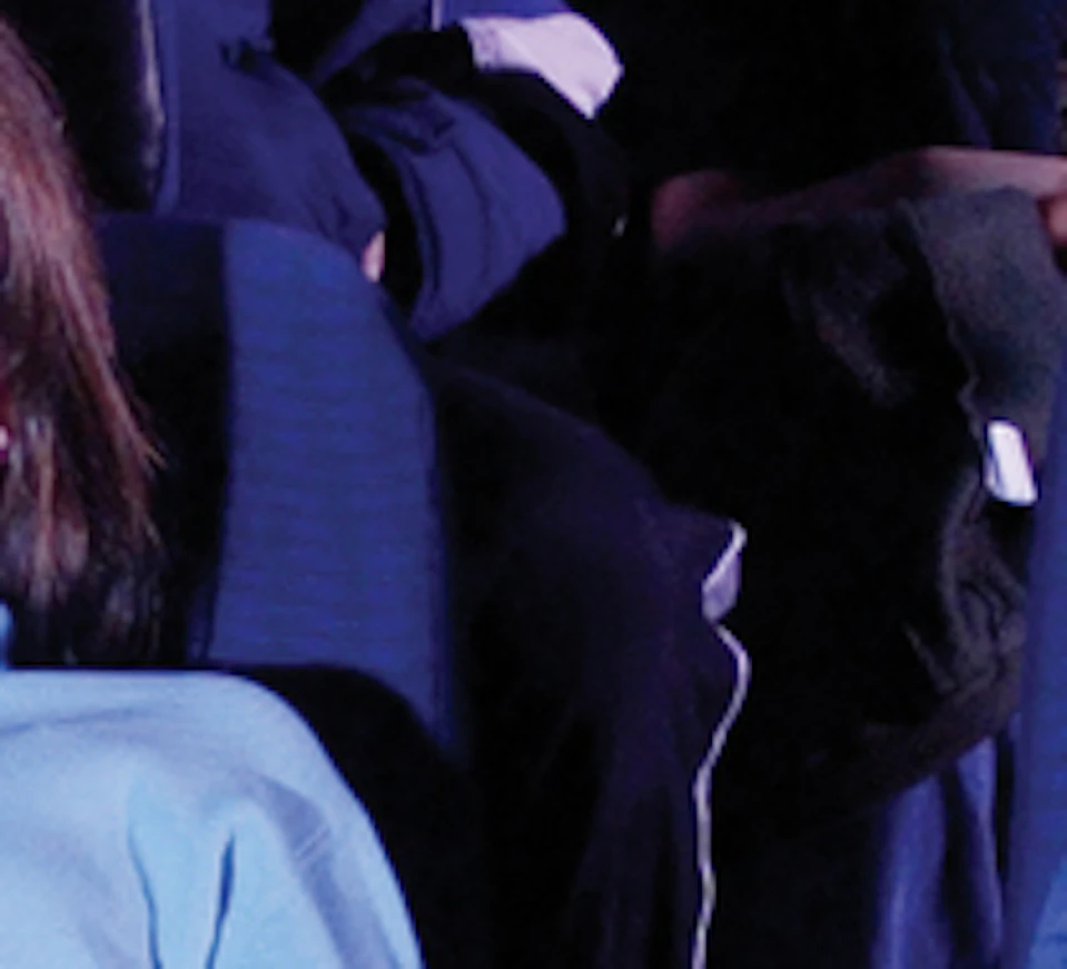 A group of people seated in a planetarium, watching a projection of planets and the sun on a domed screen.