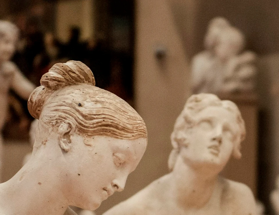 Several marble statues of women in various poses are displayed in a museum gallery.