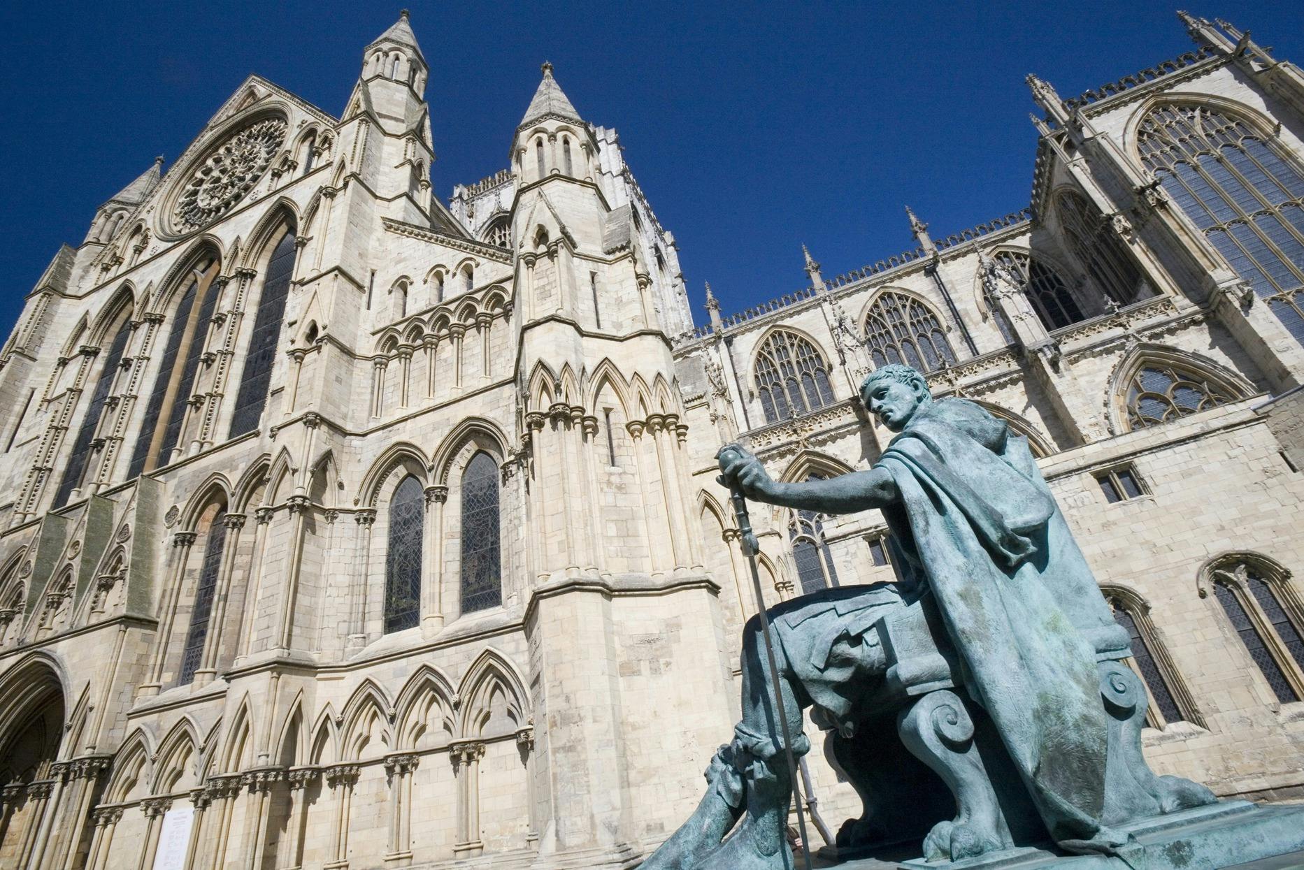 澄んだ青空の下、華やかなゴシック様式の大聖堂の前に剣を持った座像。