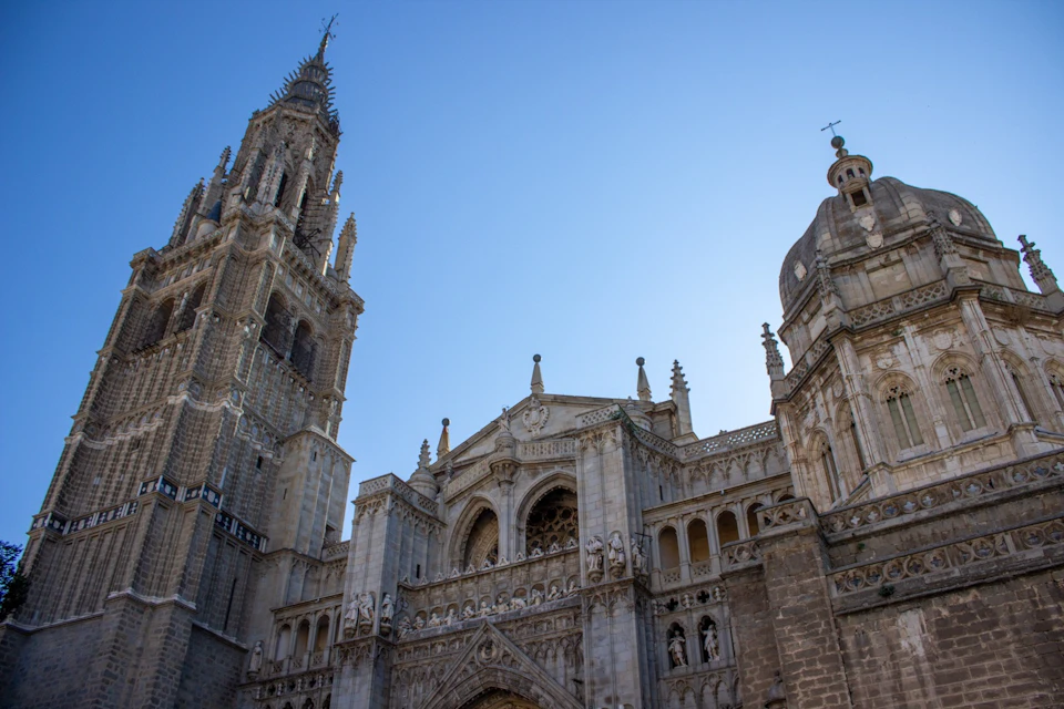 A historic Gothic-style cathedral with ornate stone detailing and tall spires under a clear blue sky.