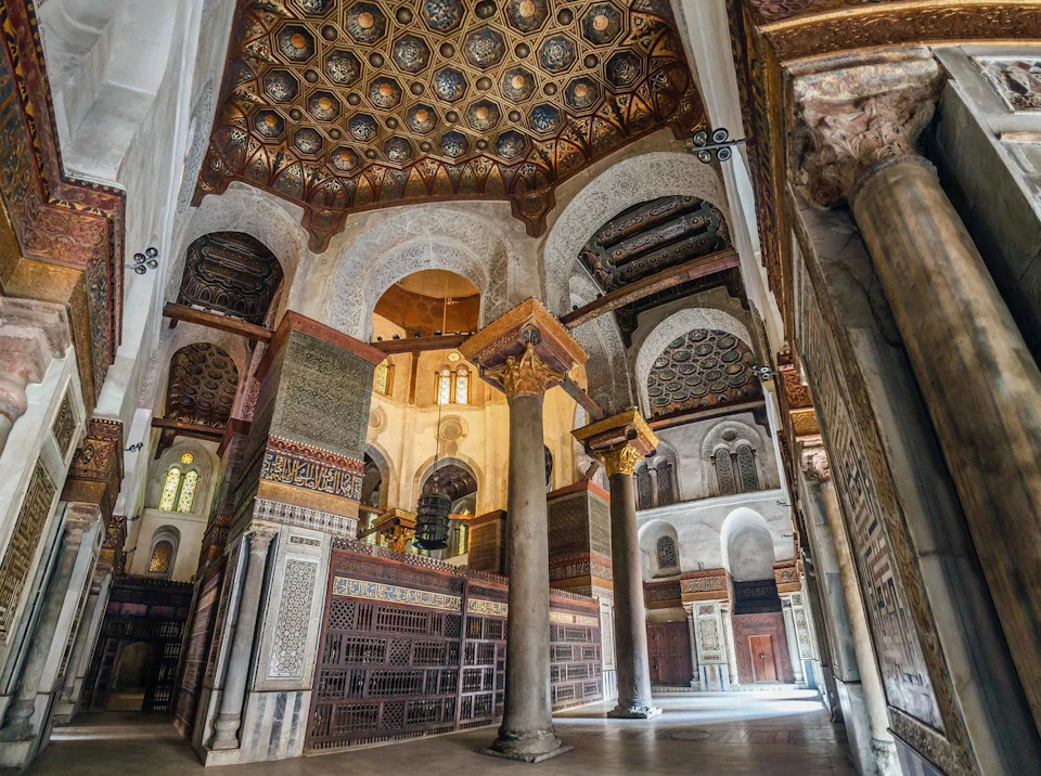 Intricately decorated interior of a historical building with arches, columns, and an ornate dome ceiling.