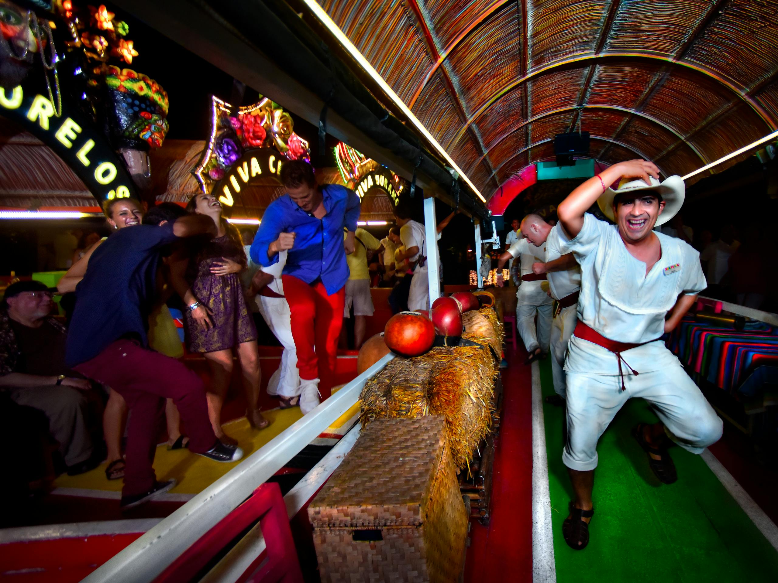 Οι άνθρωποι χορεύουν ενεργητικά σε μια γιορτινή βάρκα με ζωντανές διακοσμήσεις και σανό μπάλες, με πολύχρωμα ρούχα και χαμογελαστά πρόσωπα.