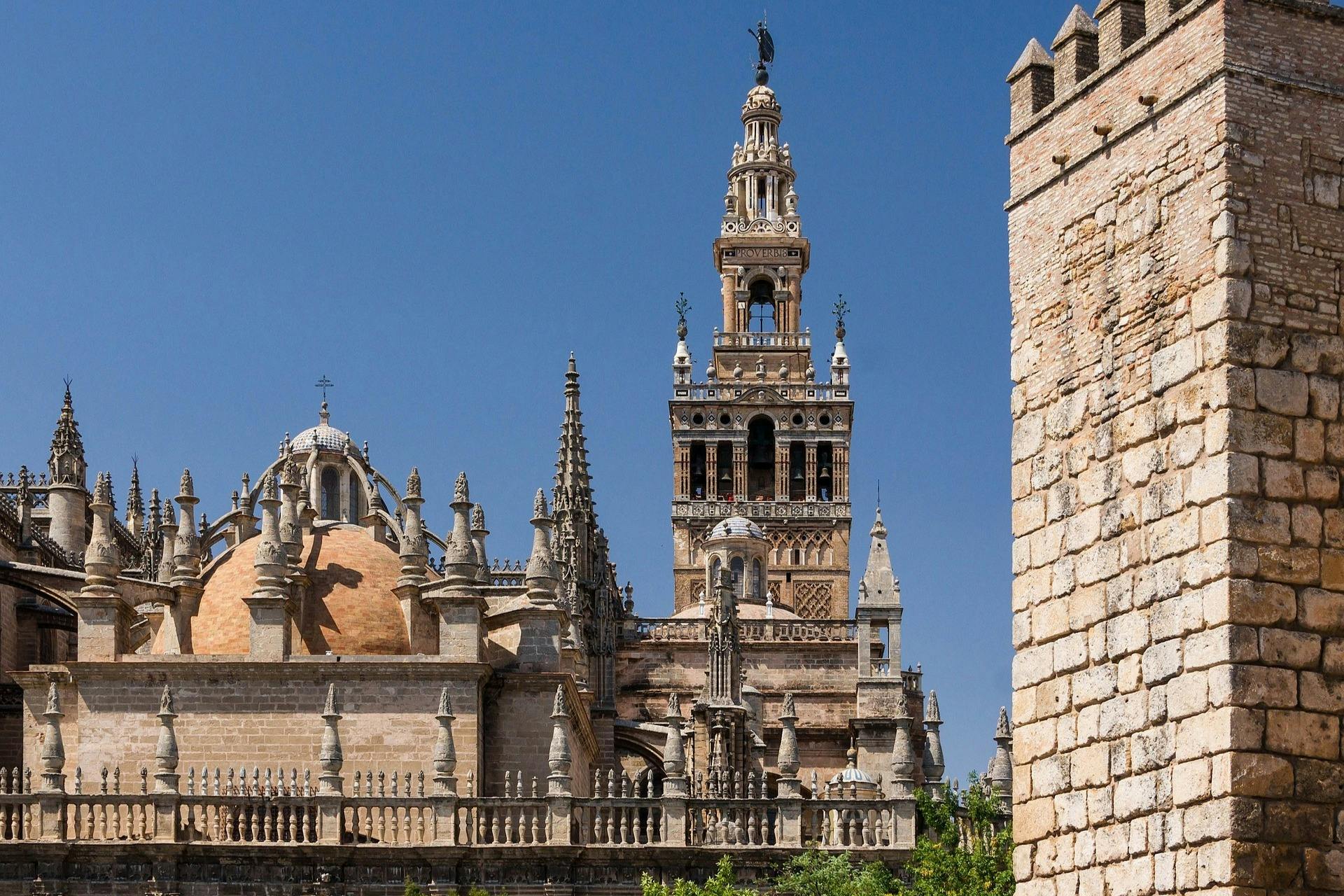 Zabytkowa katedra z ozdobnymi iglicami i wysoką dzwonnicą pod czystym, błękitnym niebem, oglądana z niskiego kąta.