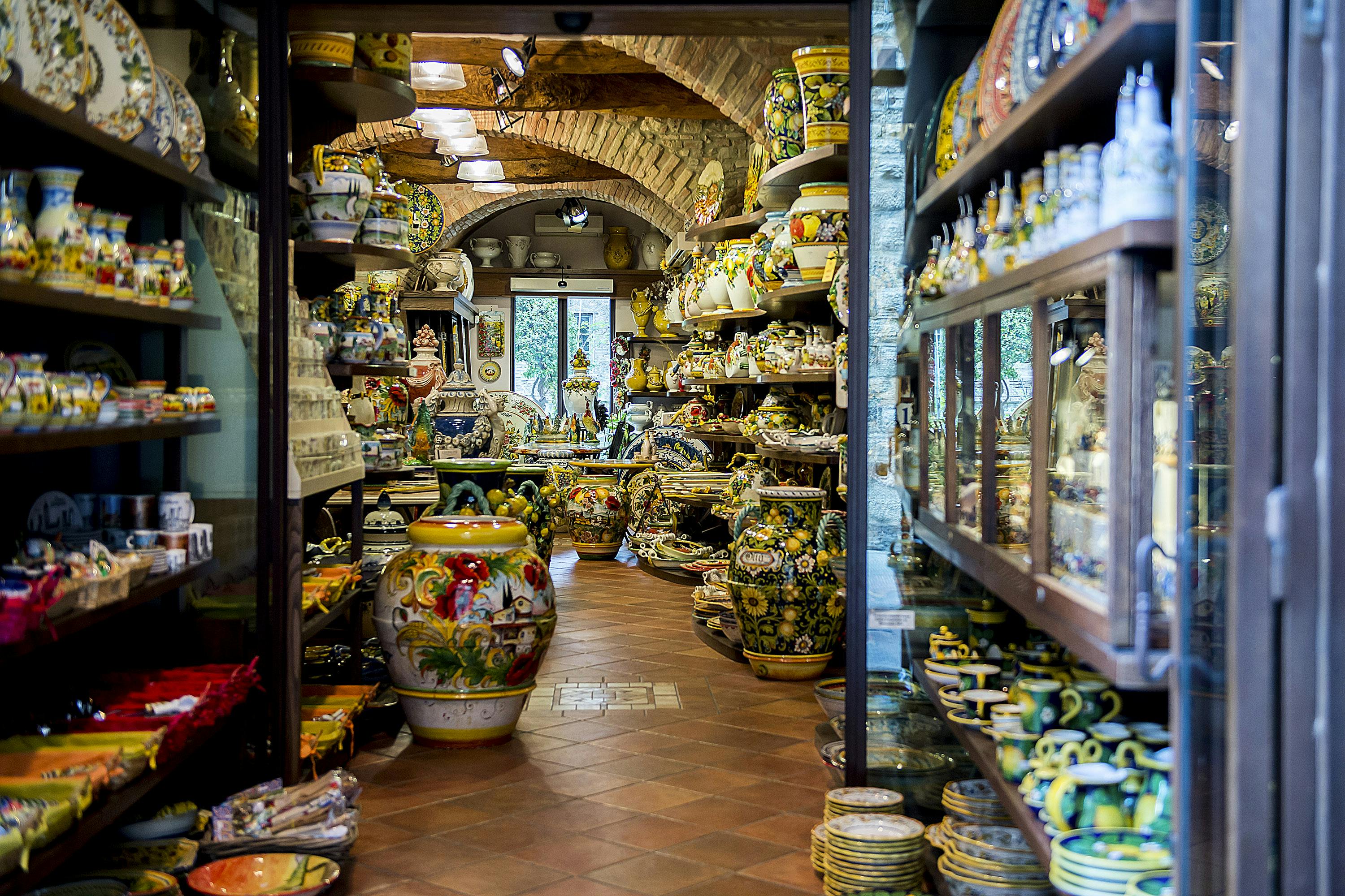 这家陶器店的架子和桌子上摆满了五颜六色的陶器，上面摆满了花瓶、盘子和各种陶器。
