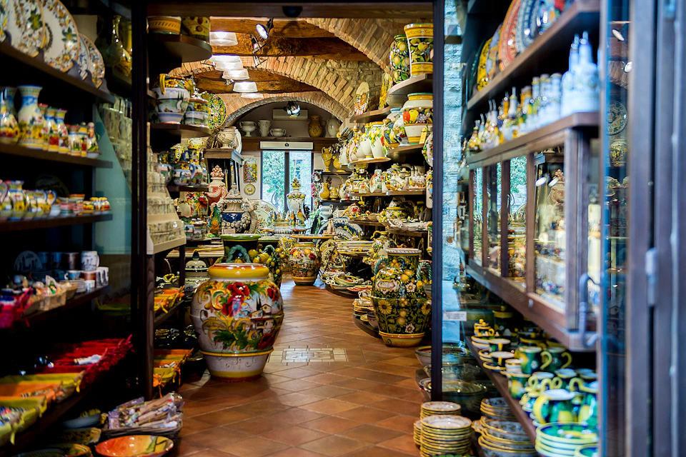 A pottery shop filled with colorful ceramics on shelves and tables, featuring vases, plates, and various pottery pieces.