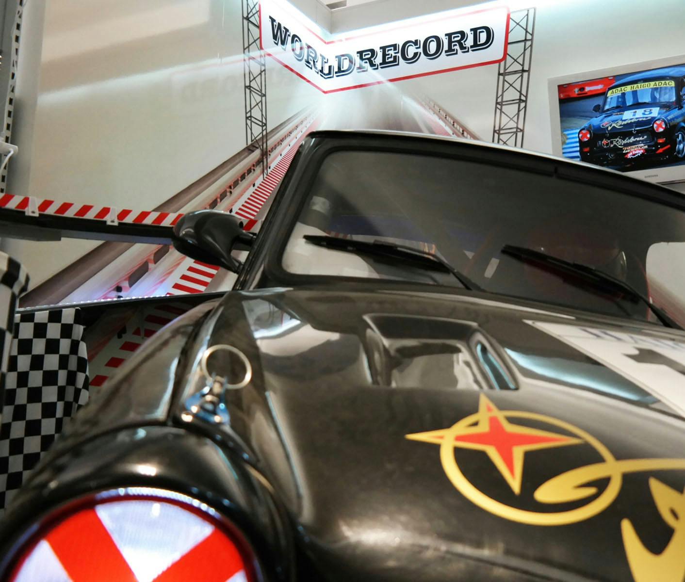 Close-up of a racing car with a "World Record" banner above it and racing tracks in the background.