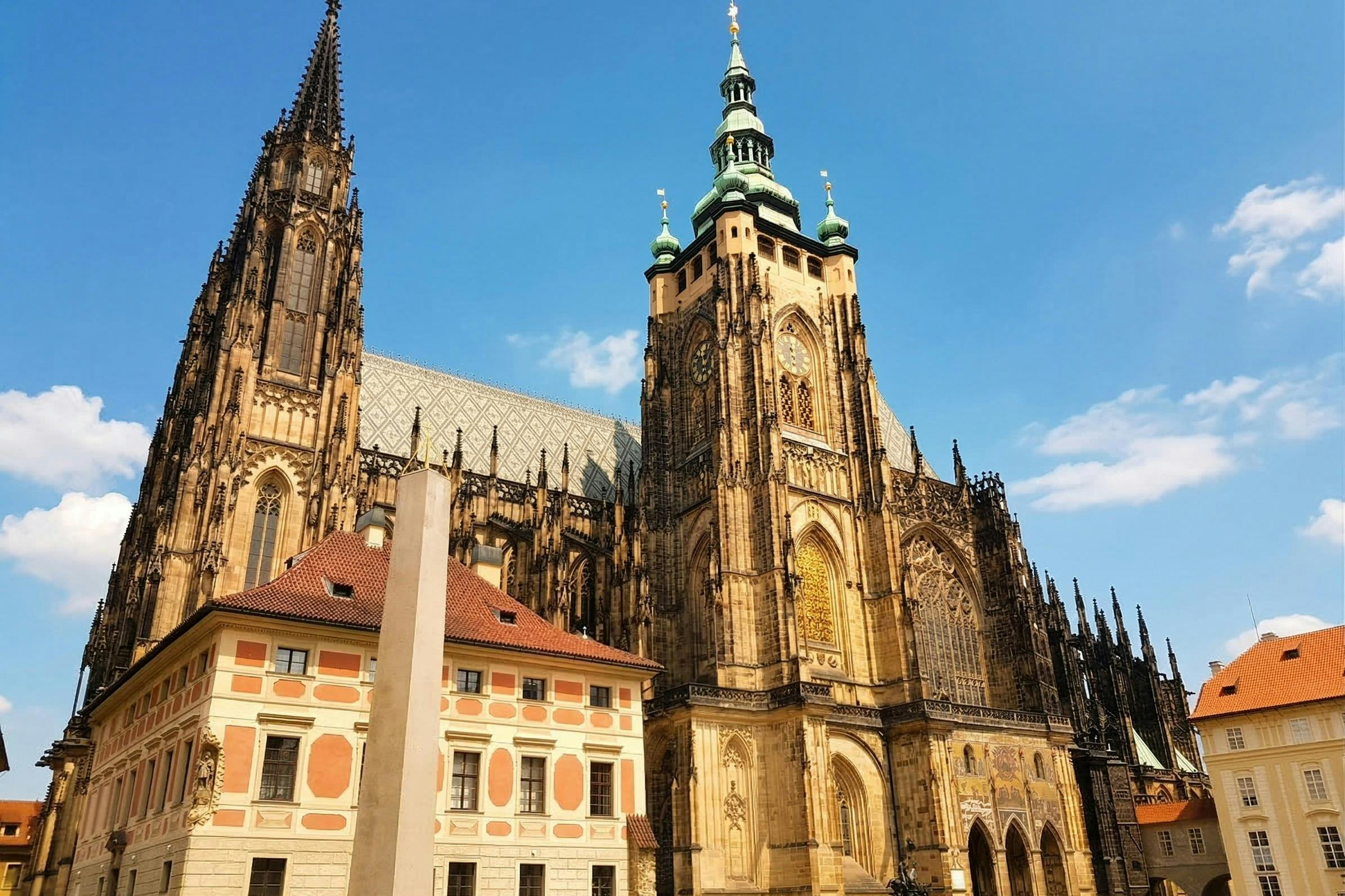 A Gothic-style cathedral with ornate details and spires, next to colorful buildings, under a clear blue sky.