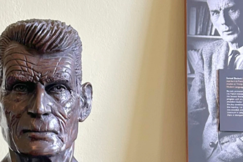A bronze bust of a man next to a panel with text and a photo of Samuel Beckett.