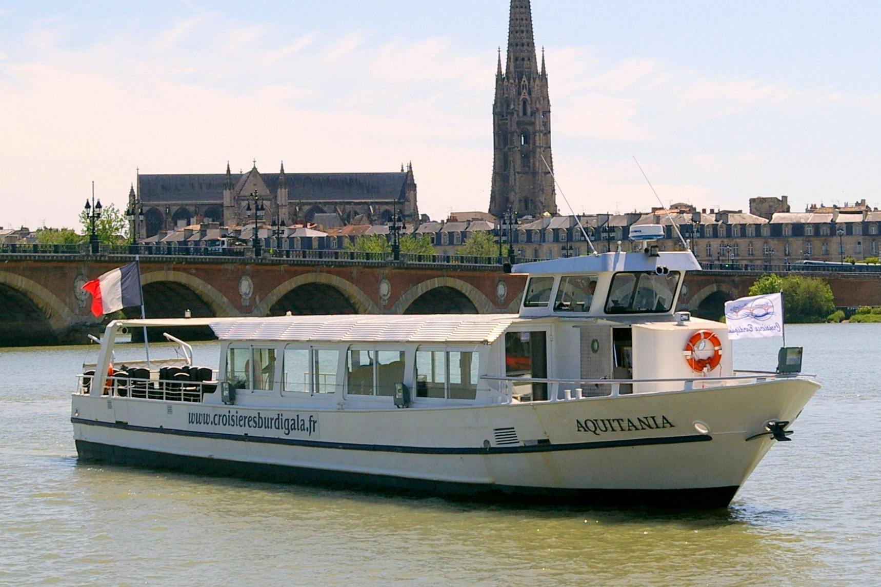 Le bateau l&#39;Aquitania naviguant face au pont de pierre avec en arrière-plan la basilique St-Michel.