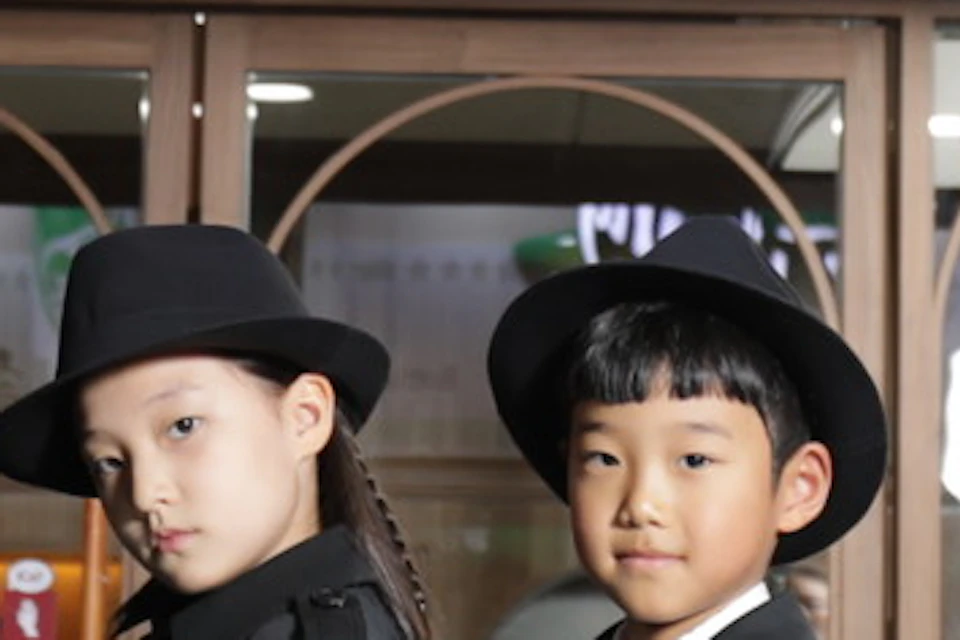 A group of children dressed in black uniforms standing in front of a Samsung store with a wood-paneled facade.