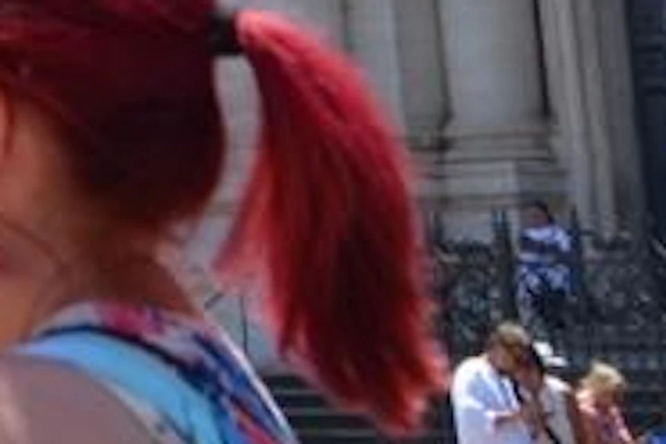Tourists in front of a baroque-style church and elaborate fountain featuring sculptures of horses and human figures.