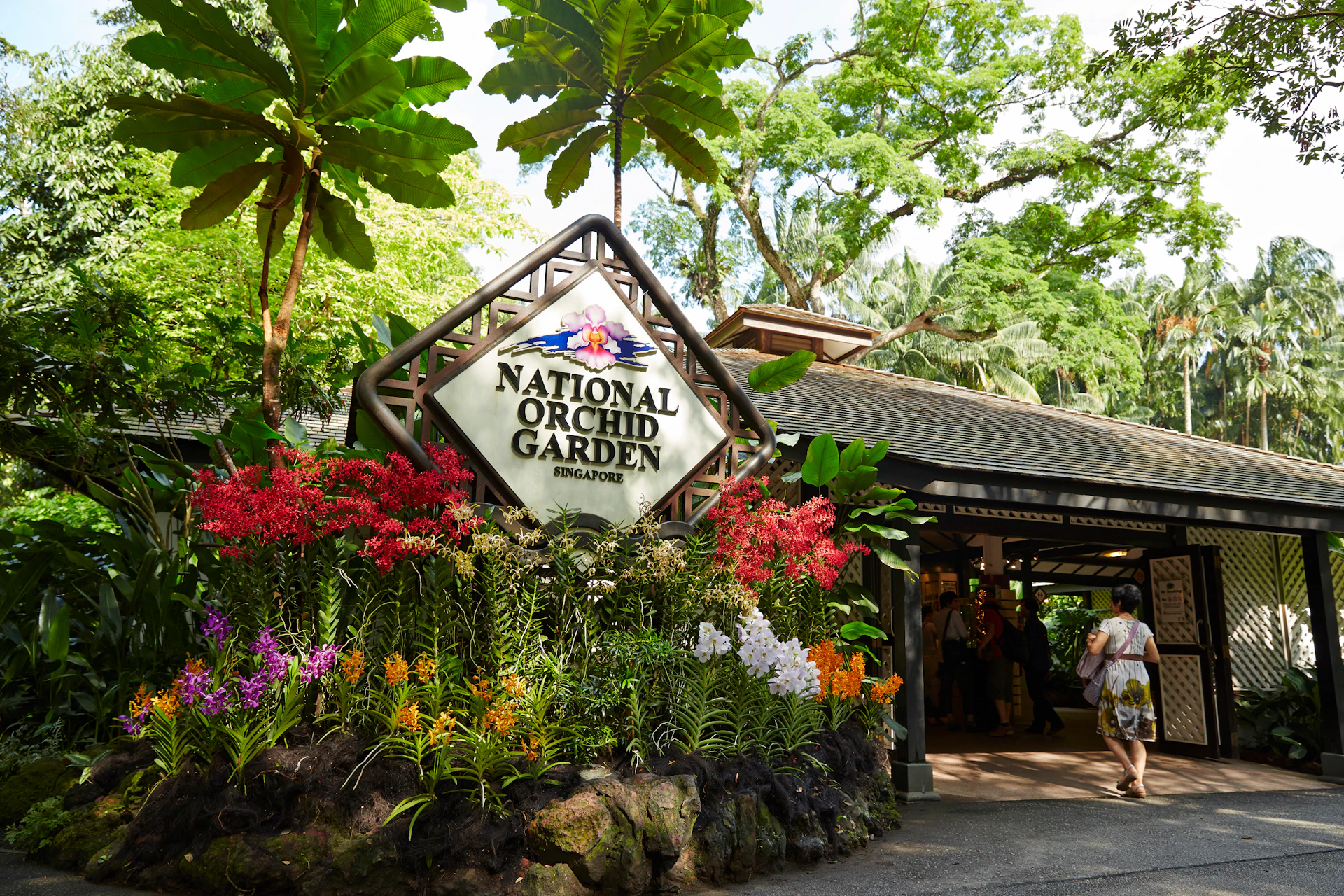 Entrance to the National Orchid Garden in Singapore, featuring a prominent sign surrounded by colorful orchids and lush greenery.