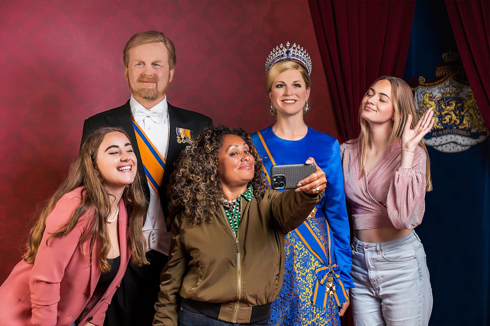 tourists posing with wax figures of the dutch royal family