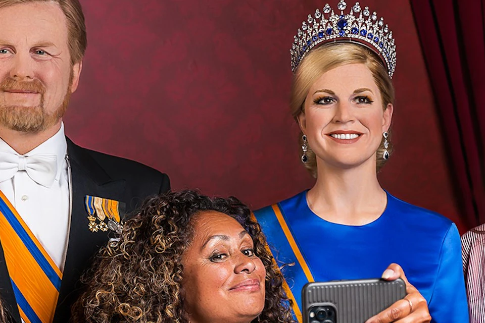 tourists posing with wax figures of the dutch royal family