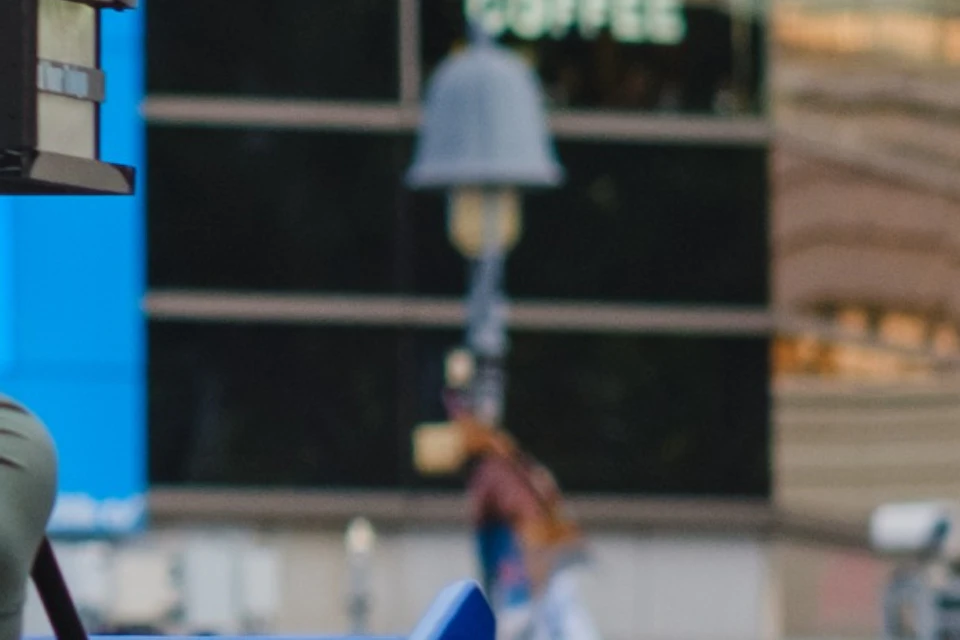 Two people driving blue go-karts on a city street, surrounded by buildings and advertisements.