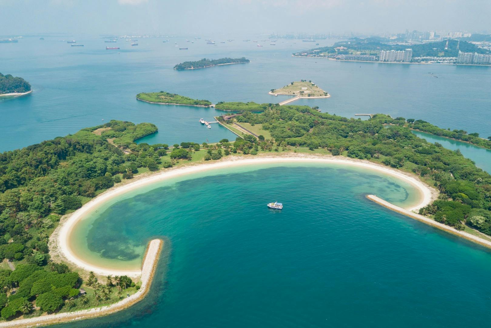 Aerial view of a tropical island with sandy beaches, lush greenery, and clear blue water, surrounded by smaller islands.
