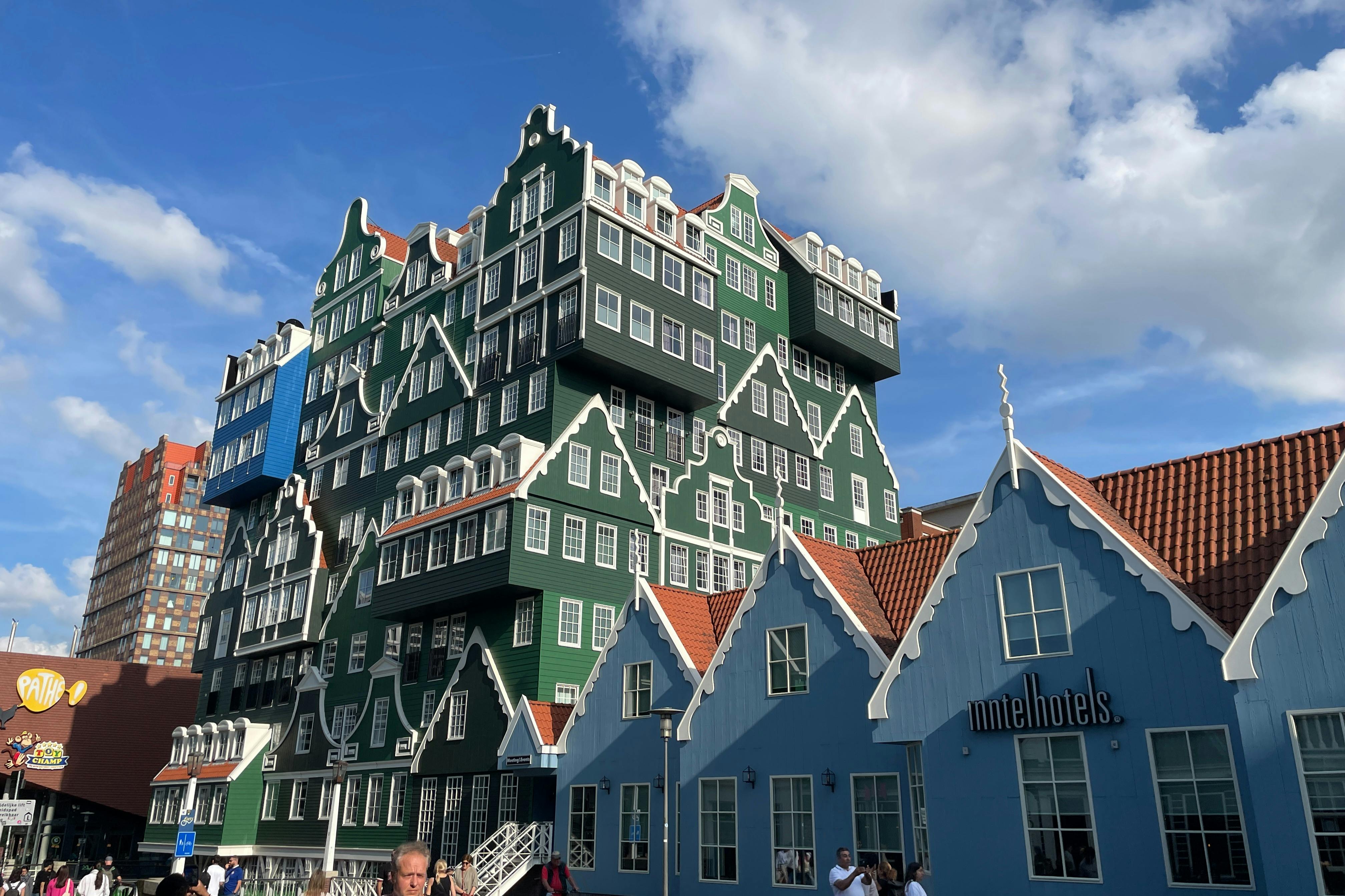 Buildings with a unique architectural style, featuring green and blue facades and steep gables, under a partly cloudy sky.