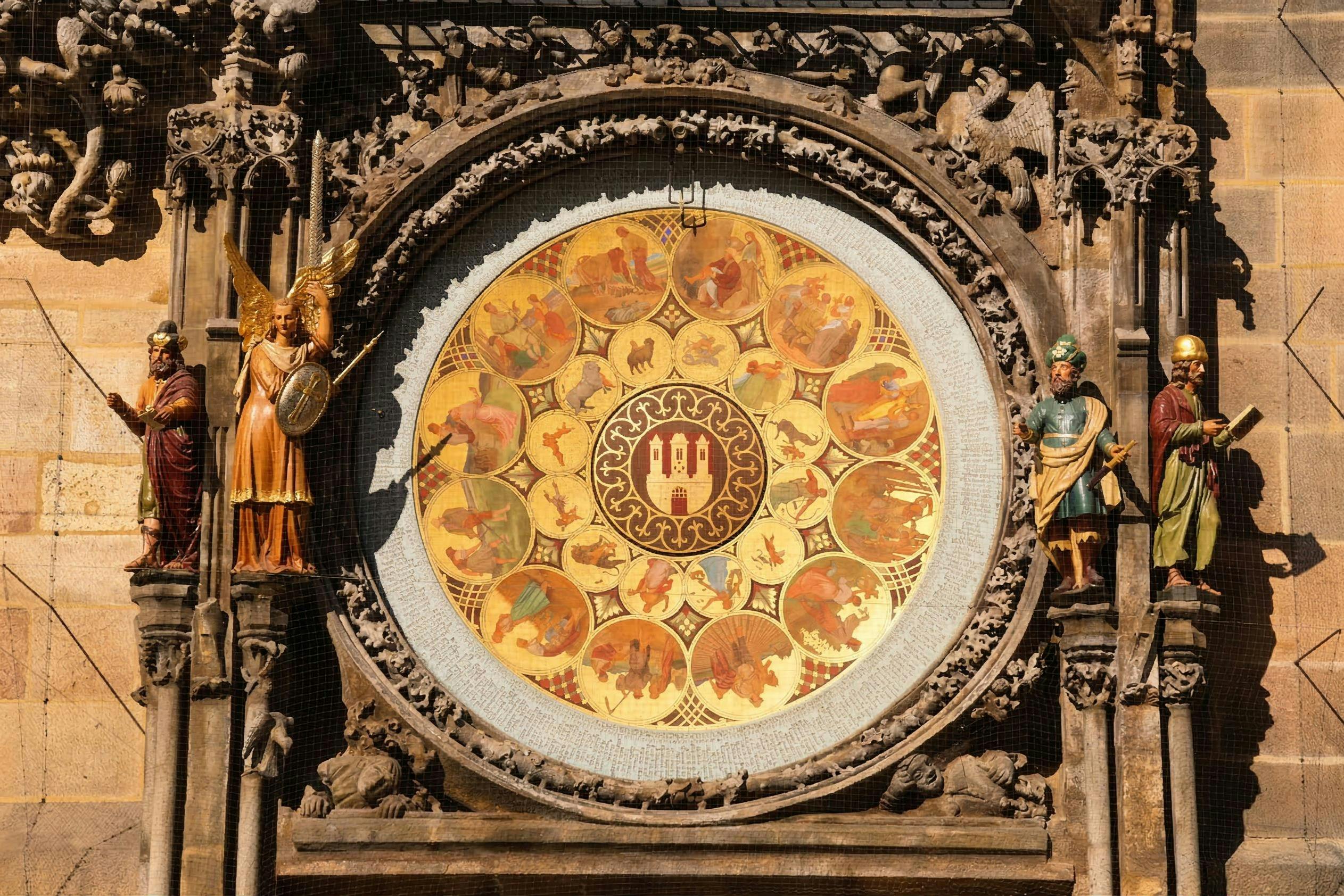 Una ornamentada esfera de reloj circular con símbolos del zodiaco, rodeada de intrincadas tallas y estatuas de figuras en un edificio histórico.