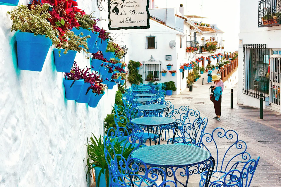 Colorful street café with blue chairs and flower pots in Mijas Pueblo